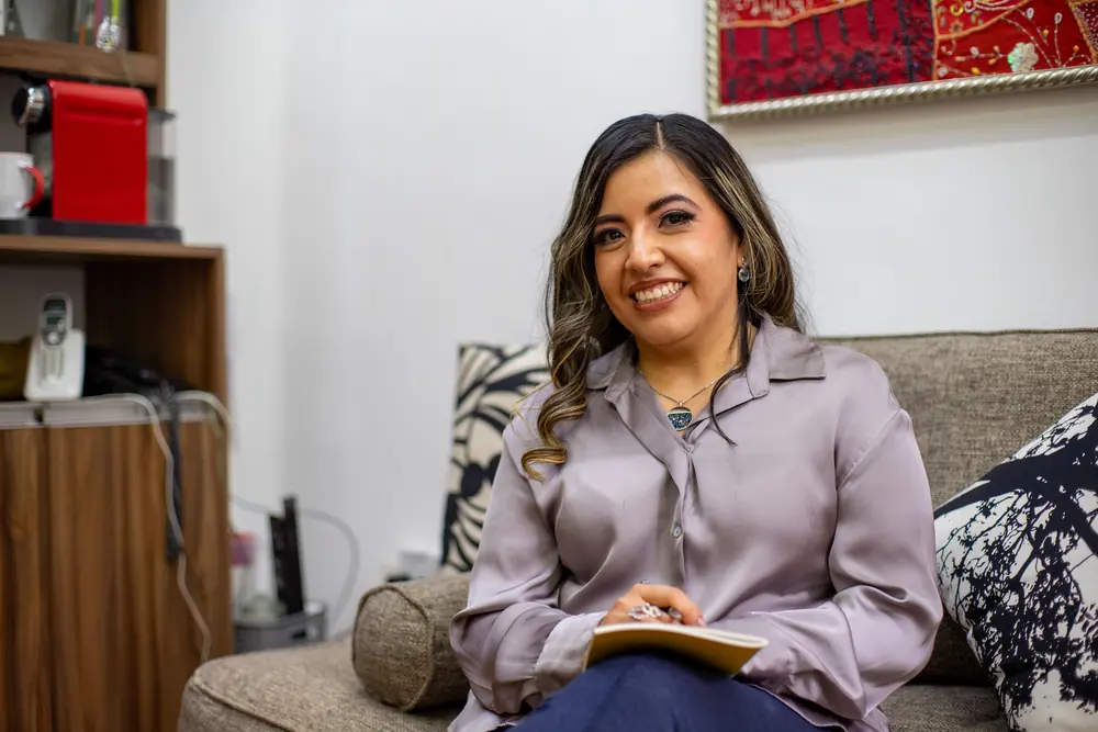 Atziri Guzmán, nutrióloga, sentada en el sofá del consultorio con una libreta en las manos