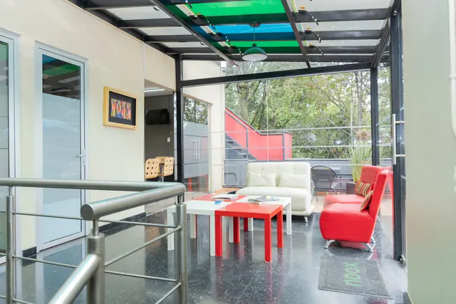 Terraza de la casa con mesa roja y vegetación