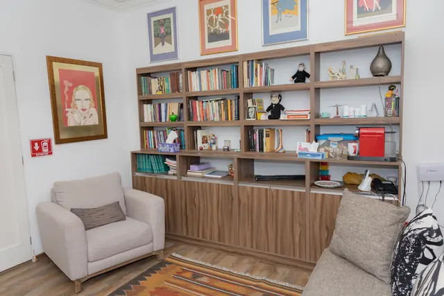Consultorio con librero lleno de libros y sillones color gris perla