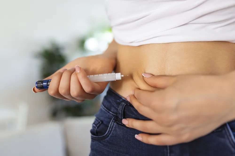Persona aplicándose insulina con una pluma en el abdomen, imagen sobre medicamentos inyectables