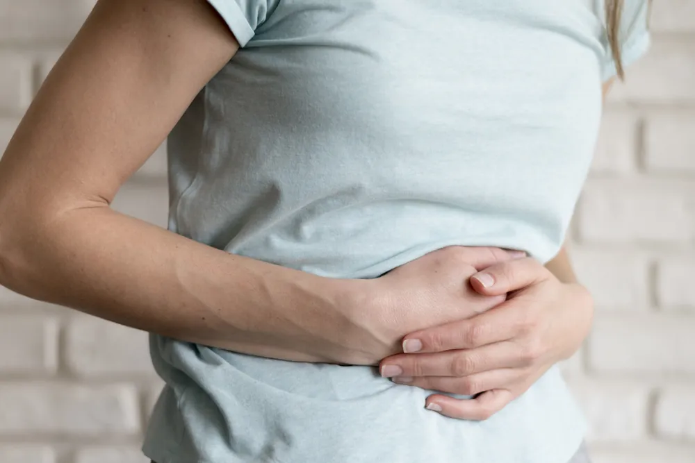 Mujer con las manos sobre el abdomen por molestias digestivas