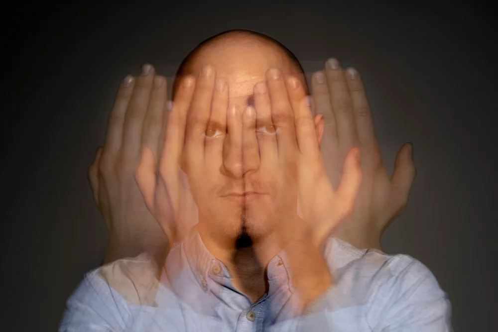Hombre con las manos frente al rostro en una exposición múltiple que sugiere varias identidades