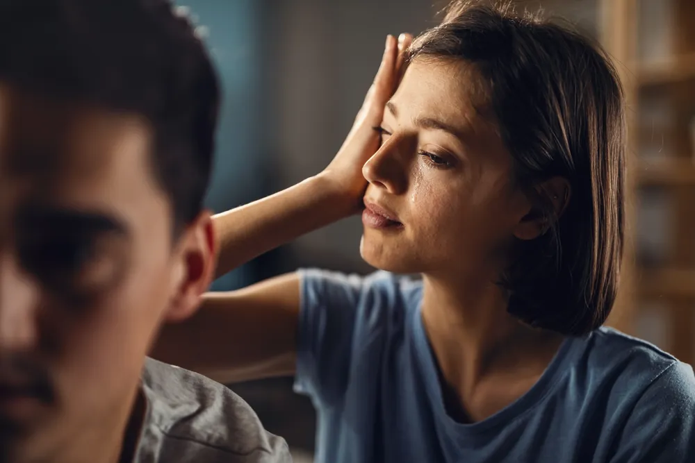 Mujer con la mano en la frente y lágrimas por un problema de relación con su pareja