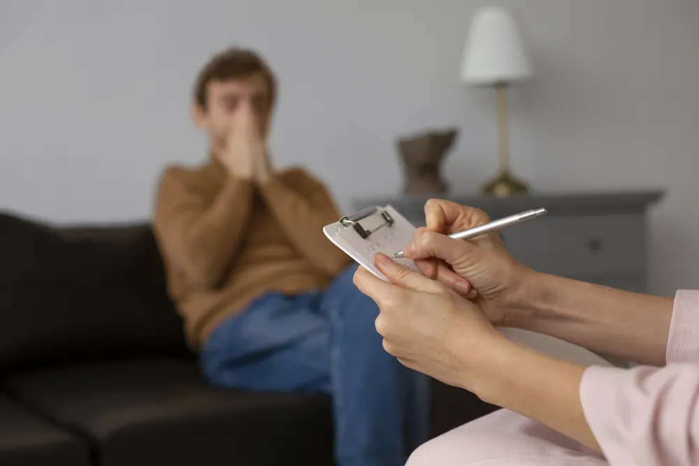 Paciente con las manos sobre el rostro sentado en un sillón durante una sesión de terapia