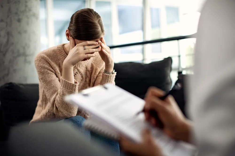 Paciente con las manos sobre el rostro durante una sesión de terapia en el consultorio